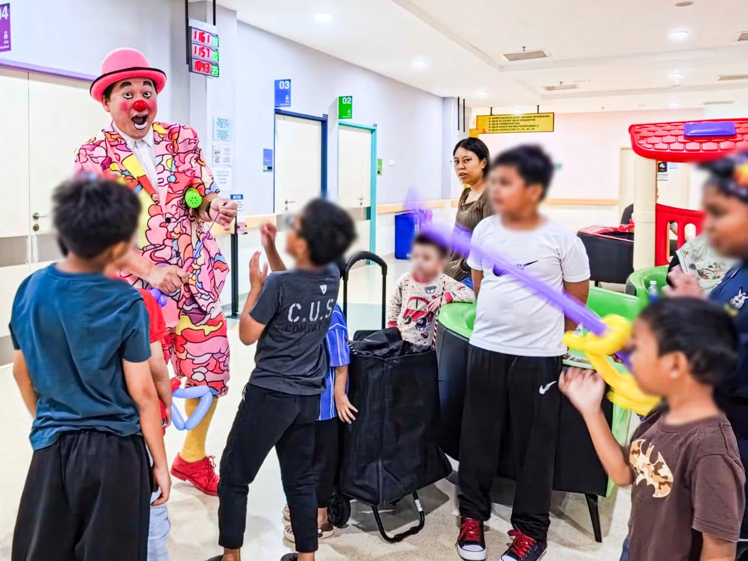 Caring Clown making balloon art with children in a hospital corridor