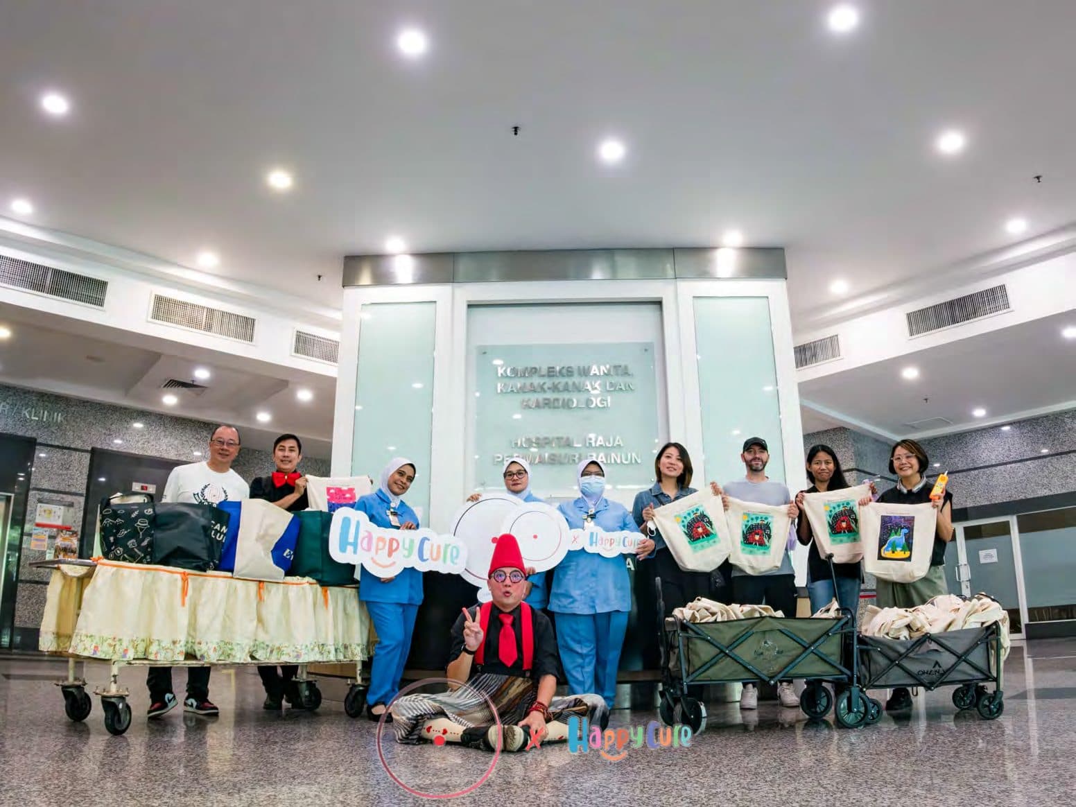 Happy Cure team and hospital staff holding tote bags at Hospital Raja Permaisuri Bainun